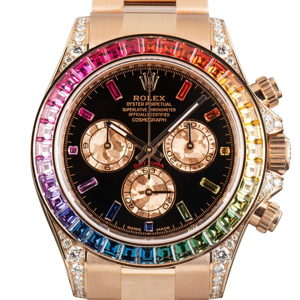 Rolex Cosmograph Daytona 116595RBOW with a black dial with sapphire hour markers and a rainbow sapphire bezel in Everose gold on an Oyster bracelet, a pre-owned example, studio close-up of the case