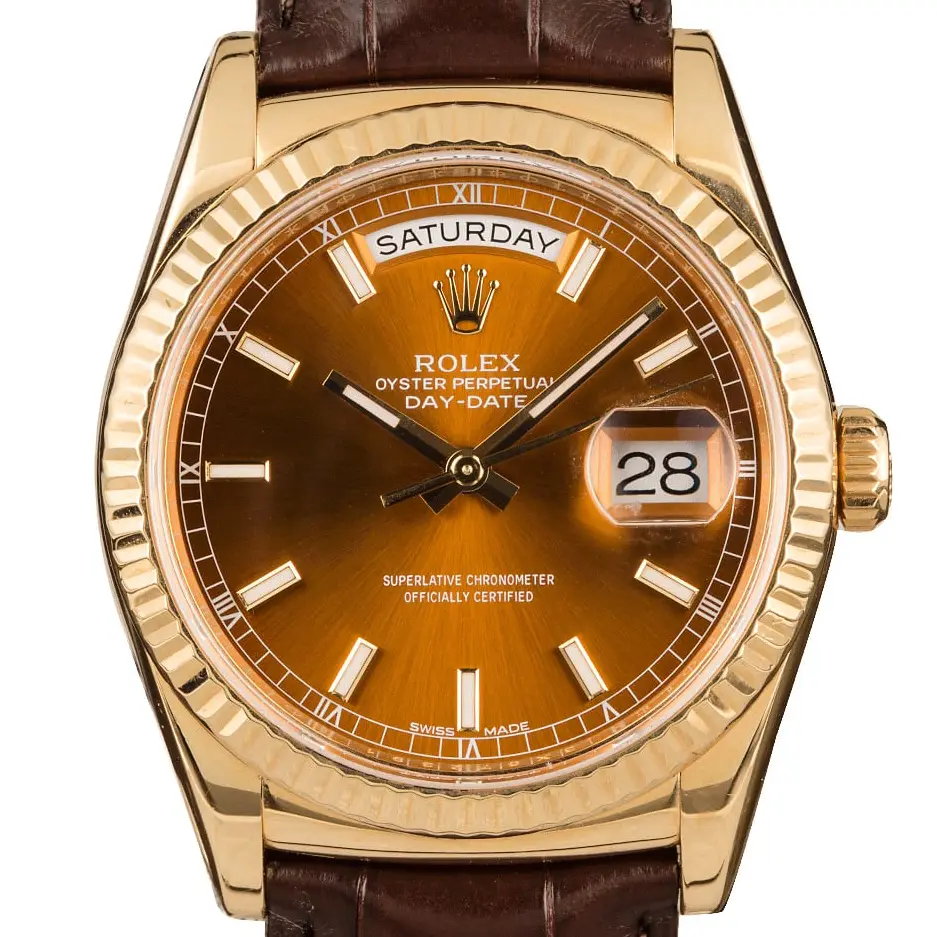 Rolex Day-Date 36 118138 with a cognac dial and fluted bezel in yellow gold on a brown leather strap, a pre-owned example, studio close-up of the case