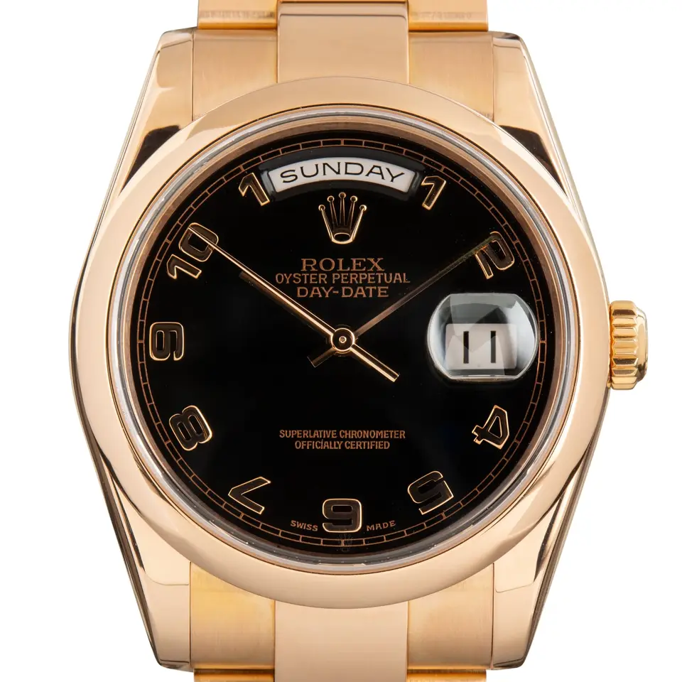 Rolex Day-Date 36 118205 with a black dial with Arabic numerals and smooth bezel in Everose gold on an Oyster bracelet, a pre-owned example, studio close-up of the case