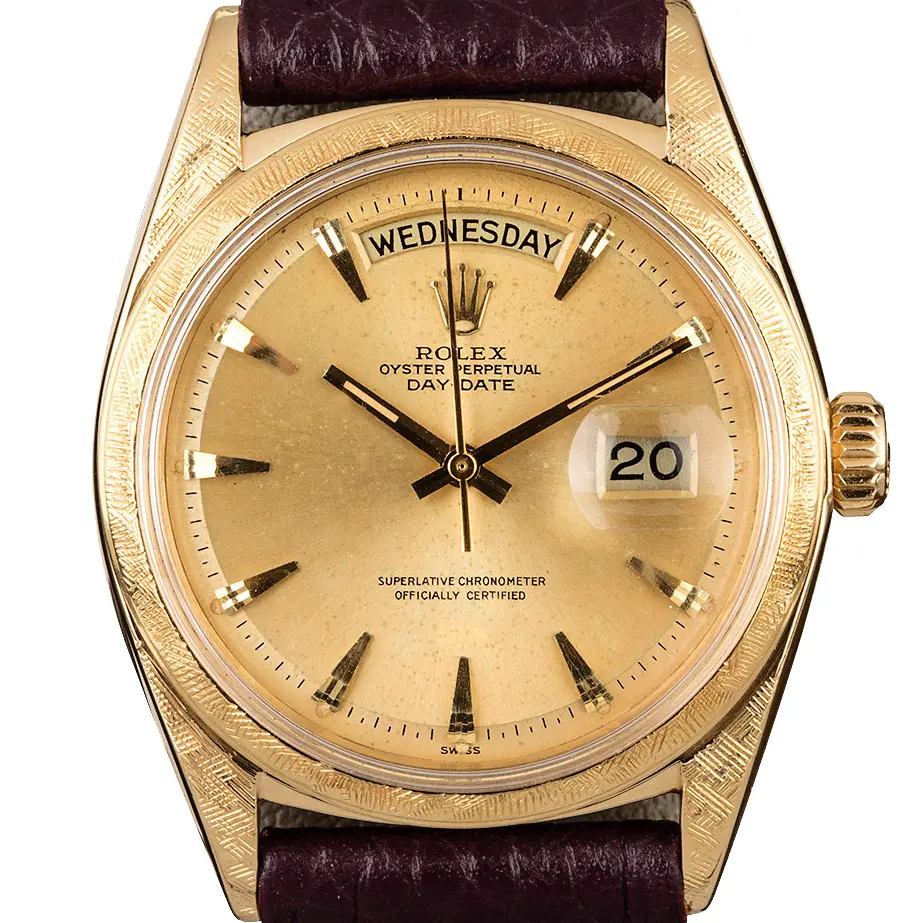 Rolex Day-Date 1806 with a champagne dial with baton markers and a textured yellow gold bezel on a black leather strap, a pre-owned example, studio close-up of the case