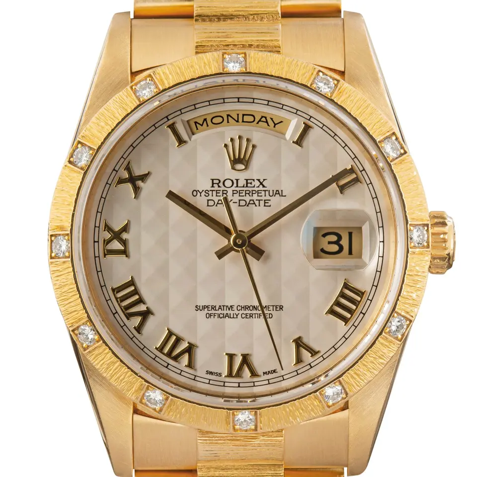 Rolex Day-Date 36 18308 with a silver pyramid Roman-numeral dial, bark-finish yellow gold bezel set with diamonds and yellow gold President bracelet, a pre-owned example, studio close-up of the case