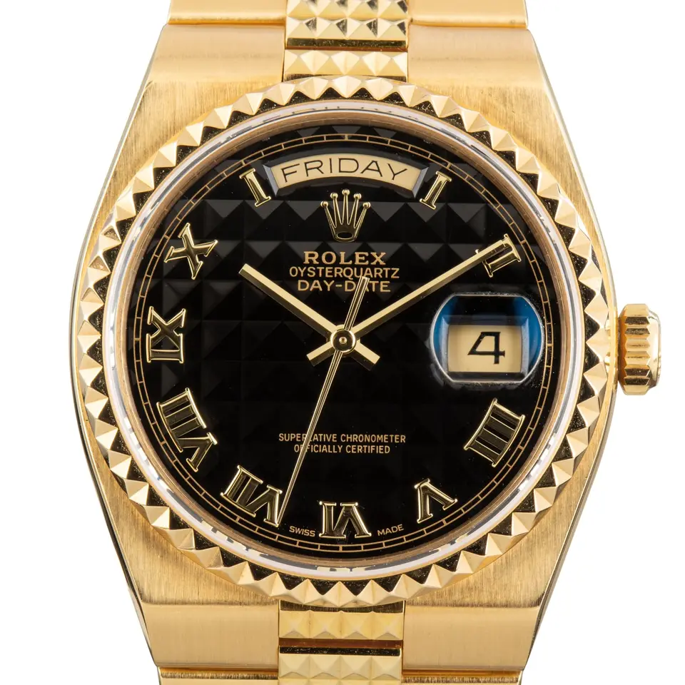 Rolex Oysterquartz Day-Date 19028 with a black pyramid Roman-numeral Oysterquartz dial, pyramid yellow gold bezel and integrated yellow gold bracelet, a pre-owned example, studio close-up of the case
