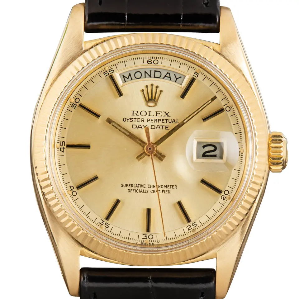 Rolex Day-Date 6611 with a champagne dial with baton markers and a fluted yellow gold bezel on a black leather strap, a pre-owned example, studio close-up of the case
