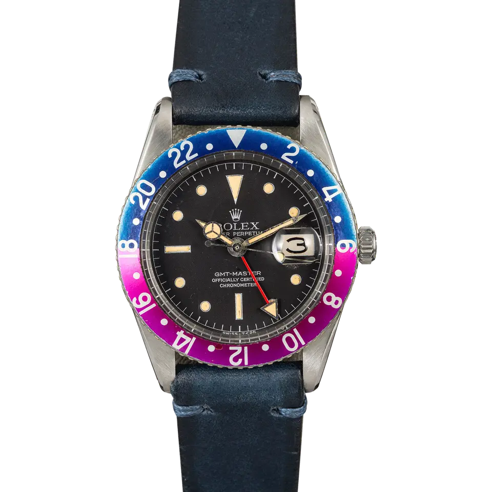 Rolex GMT-Master 6542 with a black gilt dial and a faded blue and fuchsia 24-hour bezel insert on a blue leather strap, a pre-owned example, front view of the whole watch