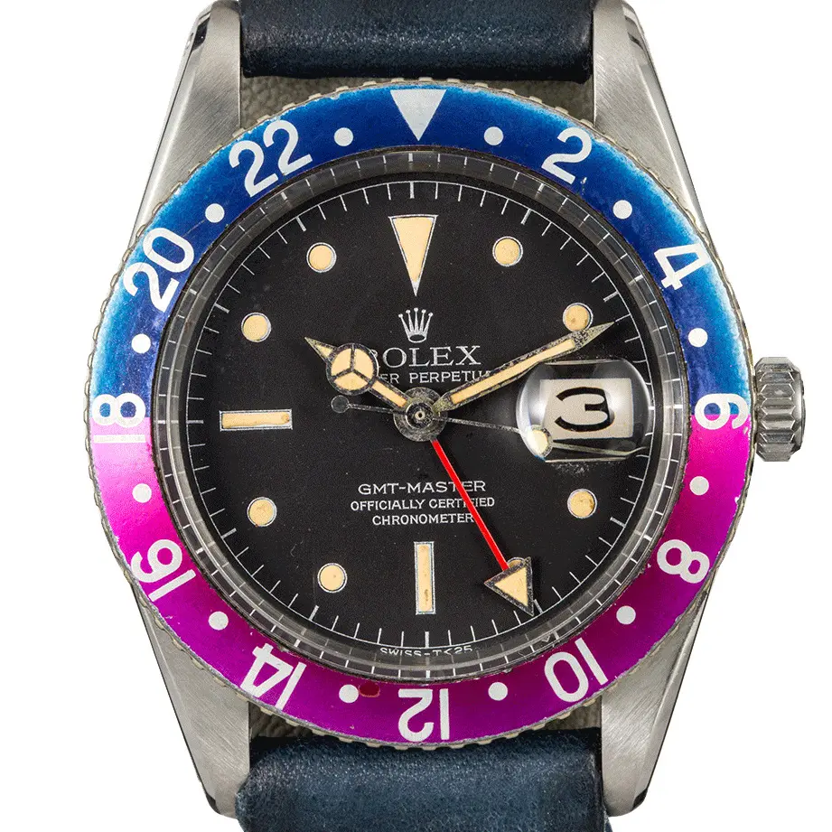 Rolex GMT-Master 6542 with a black gilt dial and a faded blue and fuchsia 24-hour bezel insert on a blue leather strap, a pre-owned example, studio close-up of the case