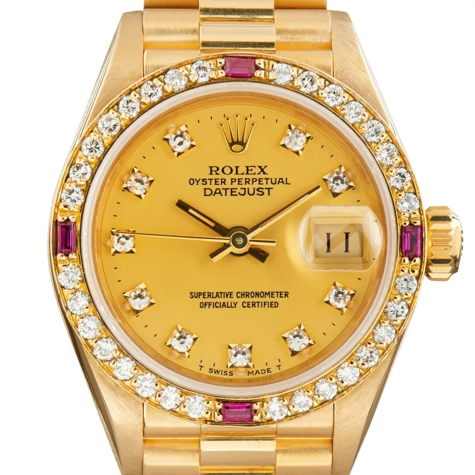 Rolex Lady-Datejust 69068 with a champagne dial with diamond hour markers, bezel set with diamonds and rubies and yellow gold President bracelet, a pre-owned example, studio close-up of the case