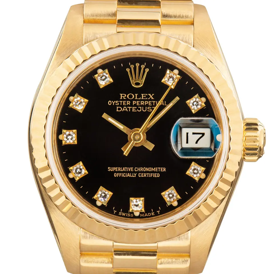 Rolex Lady-Datejust 69178 with a black dial with diamond markers and fluted bezel in yellow gold on a President bracelet, a pre-owned example, studio close-up of the case