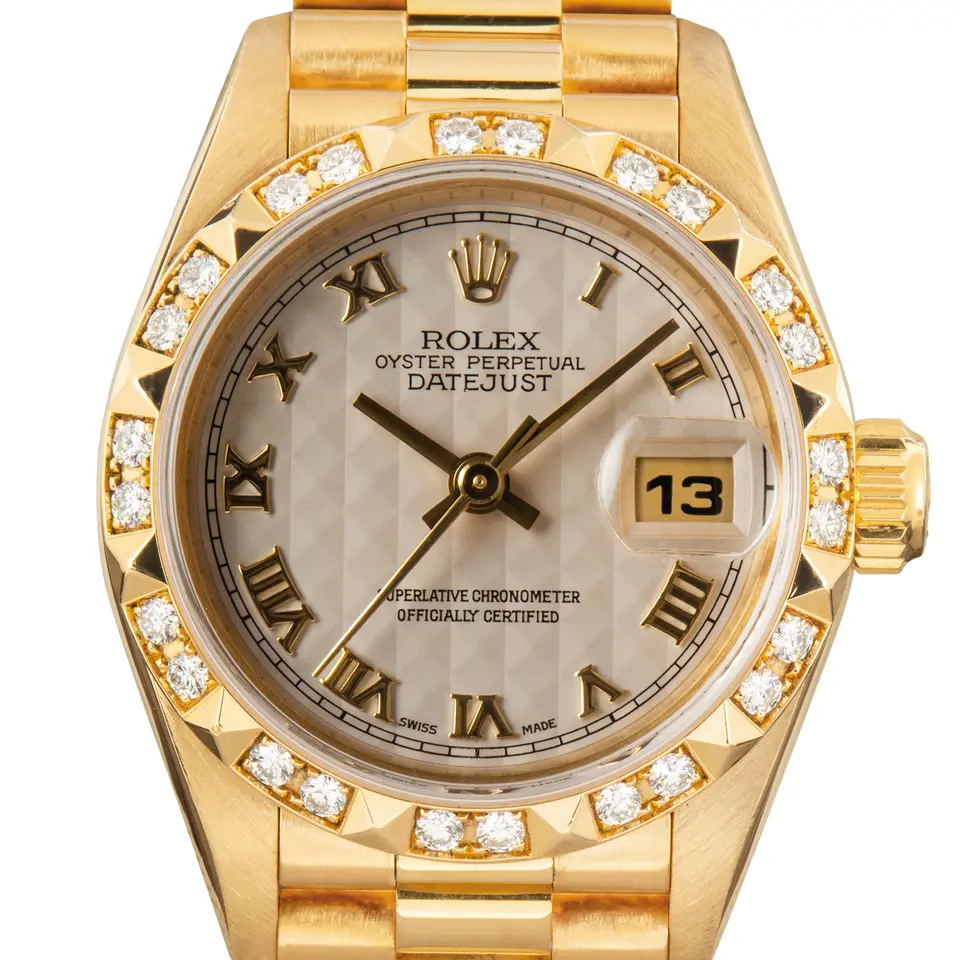 Rolex Lady-Datejust 69258 with a silver pyramid Roman-numeral dial, pyramid diamond-set bezel and yellow gold President bracelet, a pre-owned example, studio close-up of the case