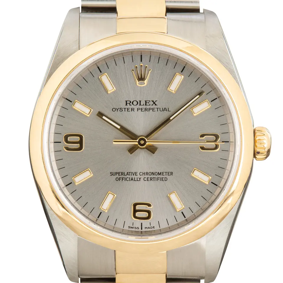 Rolex Oyster Perpetual 34 14203 with a grey dial with 3, 6 and 9 numerals, smooth yellow gold bezel and steel and gold Oyster bracelet, a pre-owned example, studio close-up of the case