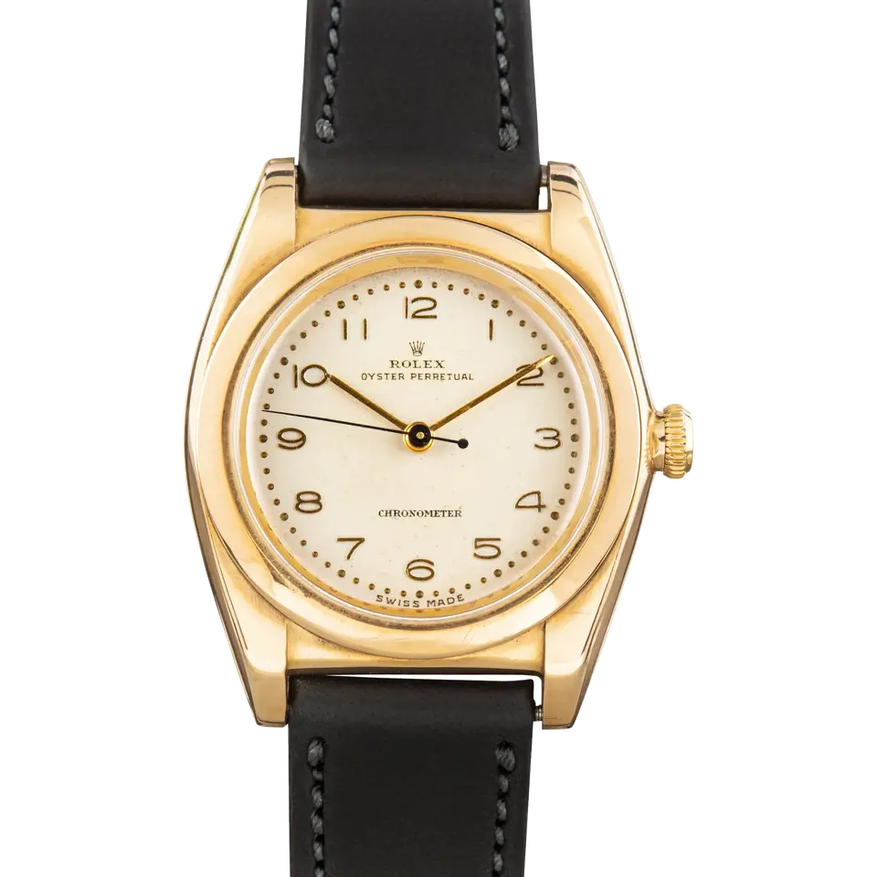 Rolex Oyster Perpetual 3131 with a cream Arabic-numeral dial, smooth gold bubbleback case on a black leather strap, a pre-owned example, front view of the whole watch