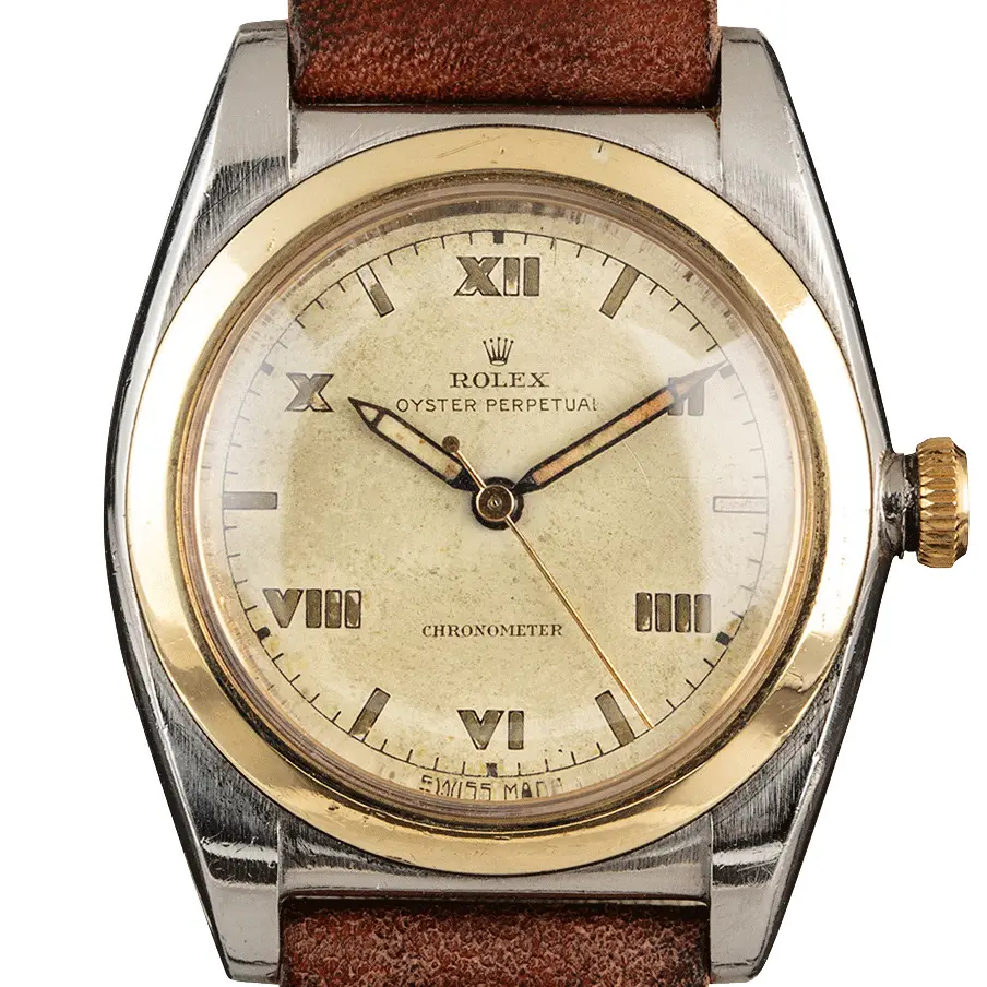 Rolex Oyster Perpetual 3133 with a cream Roman-numeral dial, smooth gold bezel and steel and gold bubbleback case on a brown leather strap, a pre-owned example, studio close-up of the case