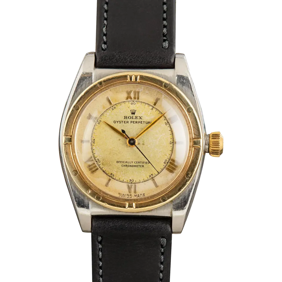 Rolex Oyster Perpetual 32 3372 with an aged cream dial, engine-turned gold bezel and steel and gold bubbleback case on a black leather strap, a pre-owned example, front view of the whole watch