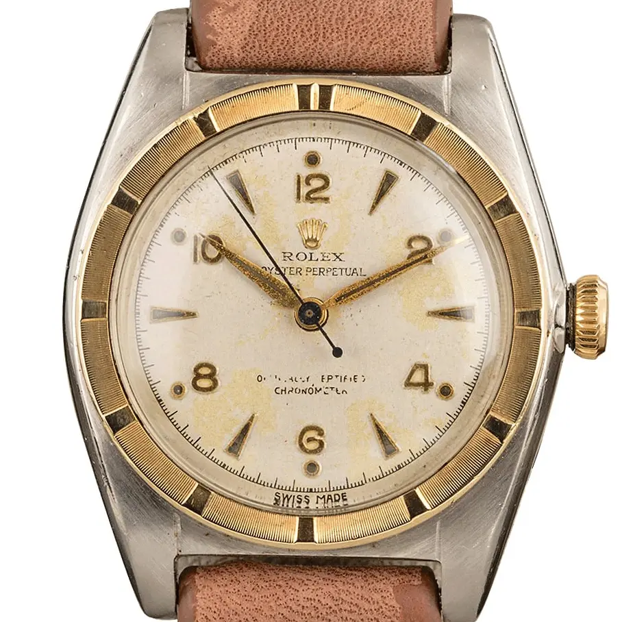 Rolex Oyster Perpetual 5015 with a cream Arabic-numeral dial, engine-turned gold bezel and steel and gold case on a brown leather strap, a pre-owned example, studio close-up of the case