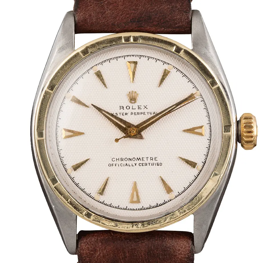 Rolex Oyster Perpetual 34 6085 with a white textured dial with arrow markers, engine-turned gold bezel and steel and gold case on a brown leather strap, a pre-owned example, studio close-up of the case