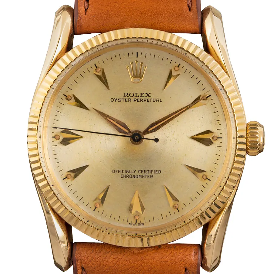 Rolex Oyster Perpetual 6593 with a champagne dial with arrow markers, fluted gold bezel and gold case on a tan leather strap, a pre-owned example, studio close-up of the case