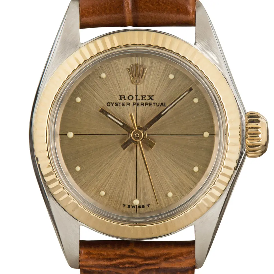 Rolex Ladies Oyster Perpetual 26 6619 with a gold sunburst dial, fluted yellow gold bezel and steel and gold case on a brown leather strap, a pre-owned example, studio close-up of the case