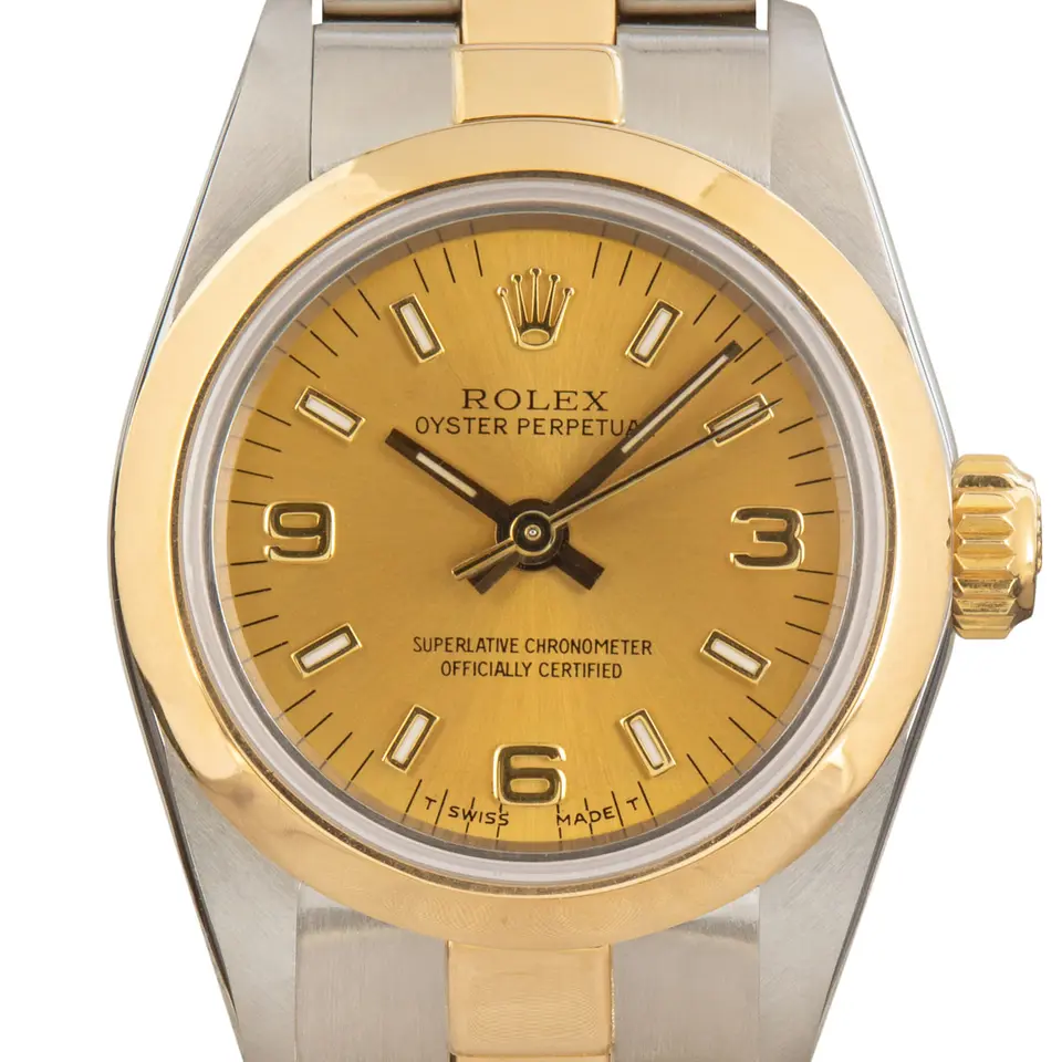 Rolex Ladies Oyster Perpetual 67183 with a champagne dial with 3, 6 and 9 numerals, smooth yellow gold bezel and steel and gold Oyster bracelet, a pre-owned example, studio close-up of the case