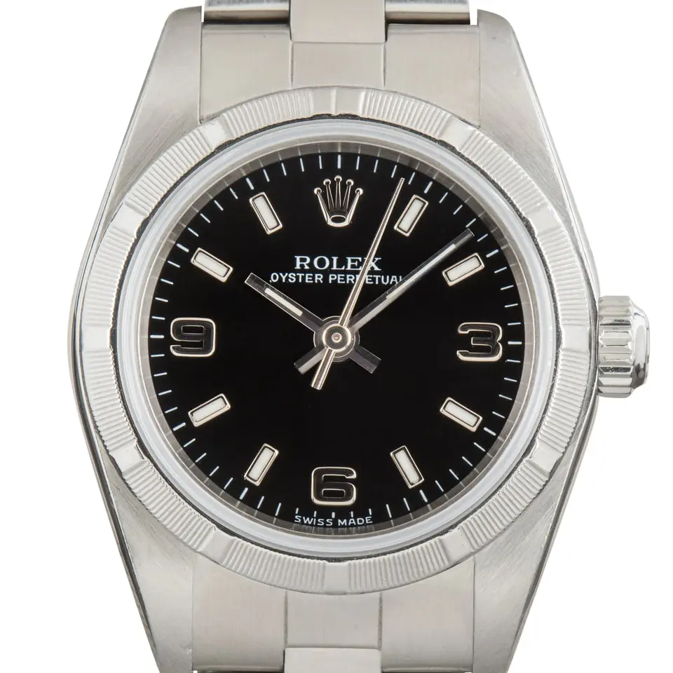 Rolex Oyster Perpetual 26 76030 with a black dial with 3, 6 and 9 numerals, engine-turned steel bezel and steel Oyster bracelet, a pre-owned example, studio close-up of the case