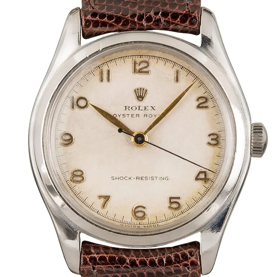 Rolex Oyster Royal 6144 with a cream Arabic-numeral dial, smooth steel case on a brown leather strap, a pre-owned example, studio close-up of the case