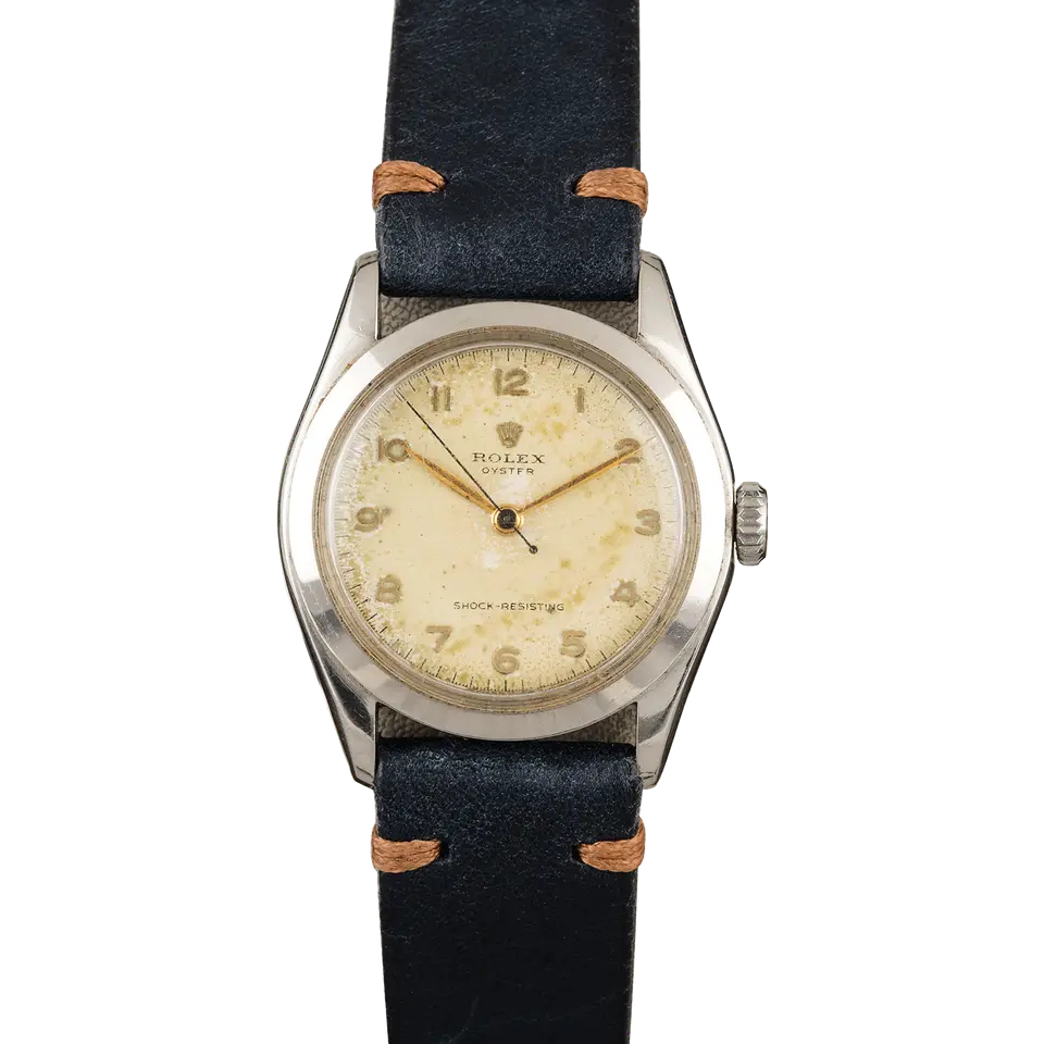 Rolex Oyster Precision 36 6082 with an aged cream Arabic-numeral dial, smooth steel case on a navy leather strap, a pre-owned example, front view of the whole watch