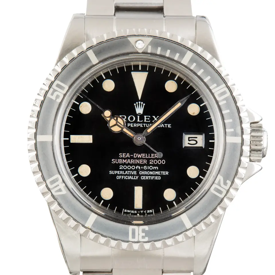 Rolex Sea-Dweller 1665 with a black dial with two red lines of text and an aged black bezel insert on a steel Oyster bracelet, a pre-owned example, studio close-up of the case