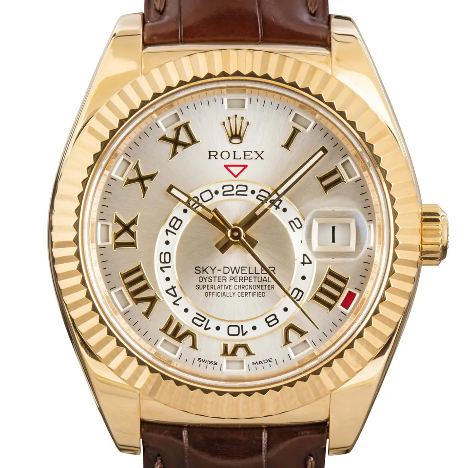Rolex Sky-Dweller 326138 with a silver dial with Roman numerals and fluted bezel in yellow gold on a brown leather strap, a pre-owned example, studio close-up of the case