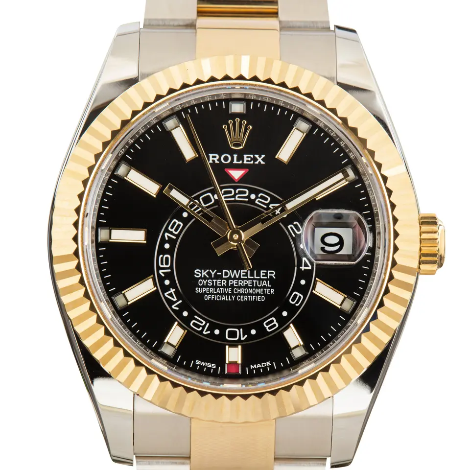 Rolex Sky-Dweller 326933 with a black dial and fluted yellow gold bezel in steel and yellow gold on an Oyster bracelet, a pre-owned example, studio close-up of the case