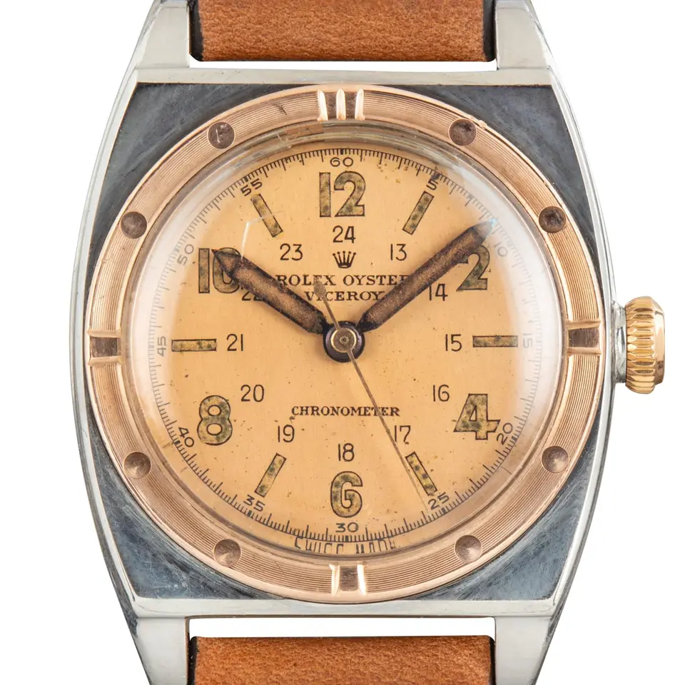 Rolex Viceroy 3359 with a salmon 24-hour Arabic-numeral dial, engraved gold bezel and steel and gold case on a tan leather strap, a pre-owned example, studio close-up of the case